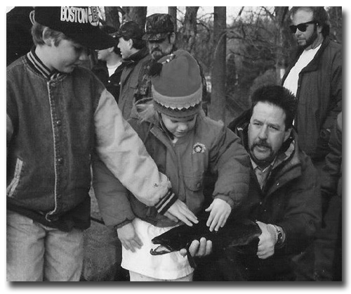 Steve Perry showing children large male salmon before stripping him of milt.