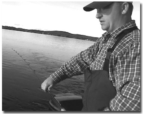 Travis letting out line to get it behind the boat. We sometimes fish right in the wake 20-30 feet back in spring, as it seems to attract the salmon.  At other times when the water is calm we go back 100-150 feet since the boat spooks them in the clear waters of Lake Winni -- especially in spring when the salmon are near the surface and easily scared.